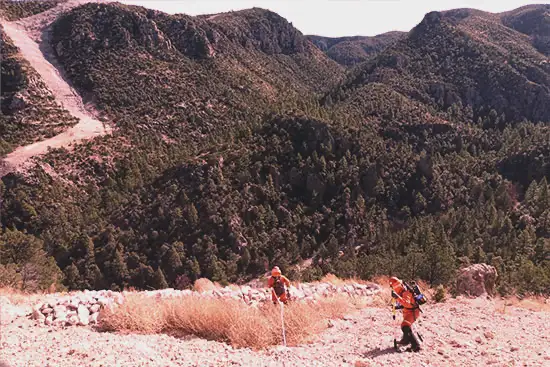 Dos trabajadores de EXDEN haciendo trabajos de inspacción de integridad mecánica de un petroducto en la sierra, con el equipo necesario de porteccion y profesional para desempeñar su trabajo con seguridad